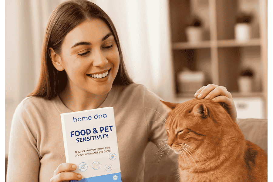 **Alt Text:** A smiling woman in a beige sweater holds a Home DNA Food & Pet Sensitivity test kit while gently petting an orange tabby cat. Is Your DNA the Reason You Feel Off?